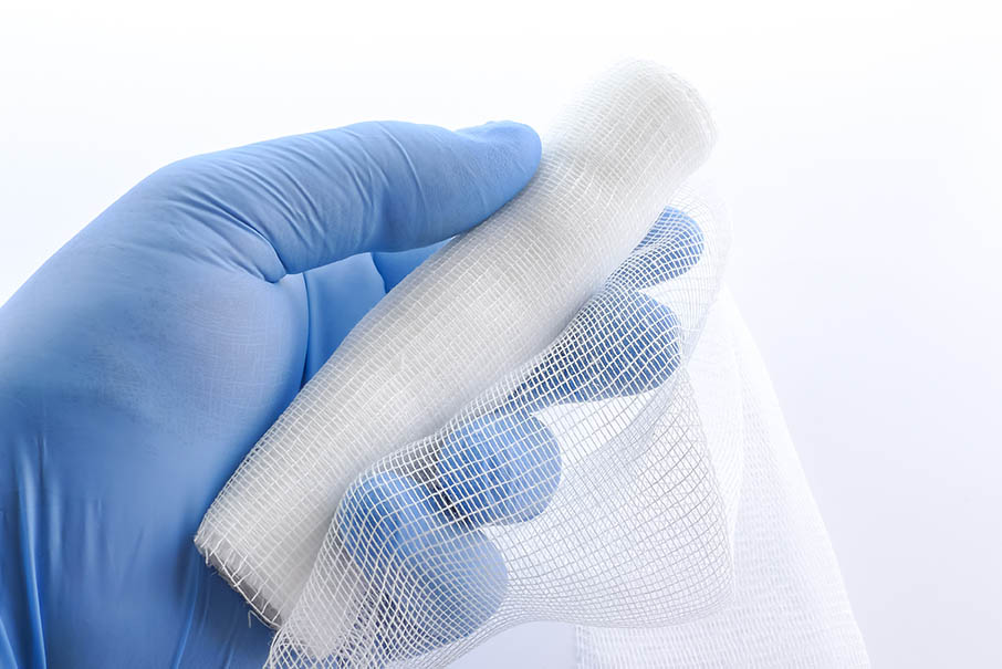 A sterile bandage in a hand. Hand holding a sterile bandage. Roll of sterile bandage.